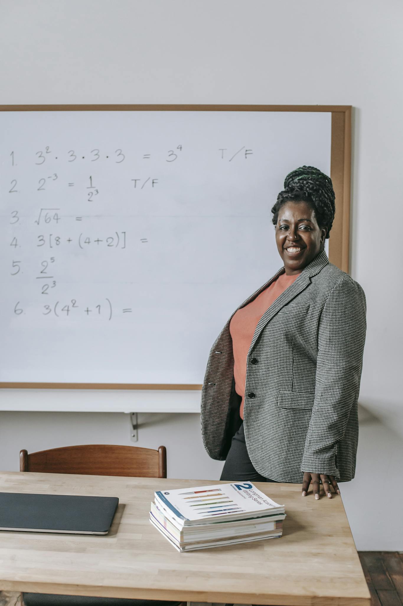 Cheerful confident African American female looking at camera near table with textbooks in classroom
