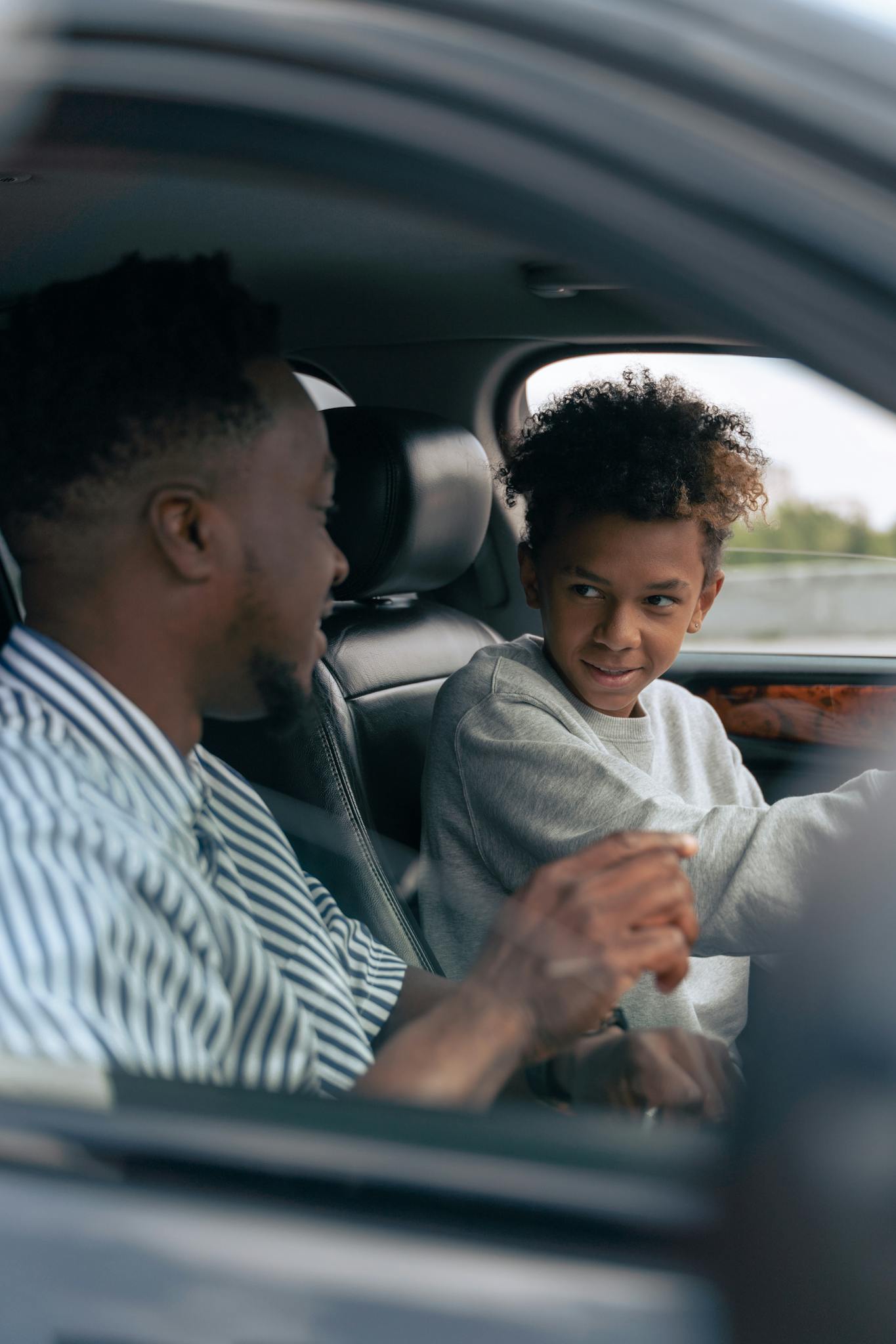 Father and son bonding inside a car, focusing on driving lessons and family time.